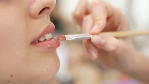 Maskenbildner trägt Lippenstift auf Modell auf Schminken in Bearbeitung.