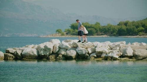 Couple Walking on Rocks by the Sea