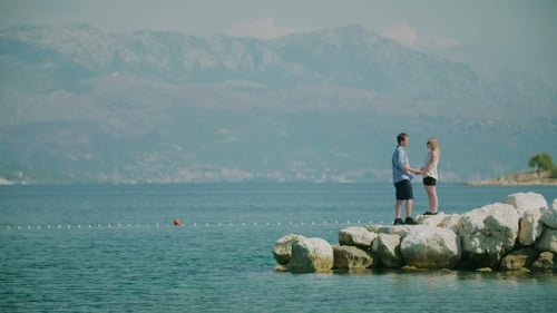 Couple Holding Hands on Rocky Beach By the Sea