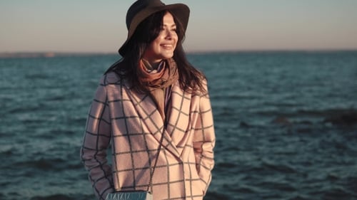 Portrait of a Young Woman on the Beach. Girl in Hat and Autumn Coat Smiling and Posing on Camera By