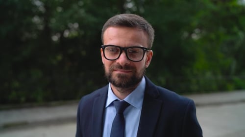 Professional Man Smiling and Adjusting Glasses Outdoors