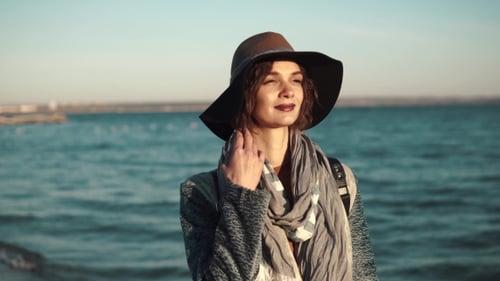 Beautiful Young Woman Walks Along the Coast, Smiling and Enjoying the Warm Autumn Day.