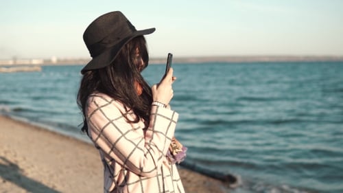 Young Woman Is Taking Photos of Her Girlfriend on Mobile Phone. Girls Are Photographed Outdoors