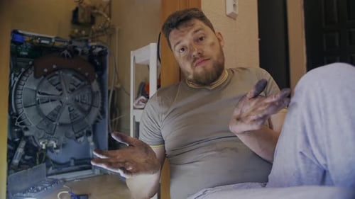 Man with Dirty Hands next to Disassembled Washing Machine