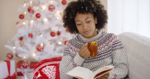 Woman Reading Book and Drinking Tea at Christmas