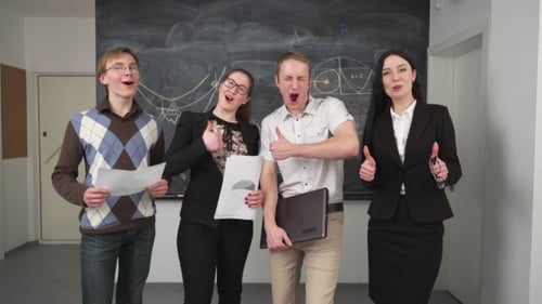Four Young Adults Giving Thumbs Up in Classroom
