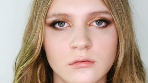 Porträt eines schönen Gesichts einer jungen Frau mit hellem Bronze-Make-up, das in die Kamera schaut, dann vor