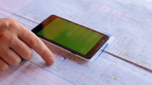 Construction engineer using a smartphone with a green screen looking for information on the internet