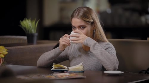 A Young and Pretty Woman Enjoys the Taste of Coffee in a Restaurant