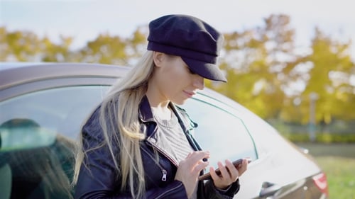 Stylish Woman Uses Smartphone Near Car Outdoors