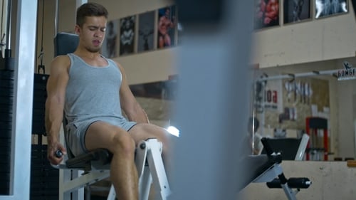 Junger athletischer Mann macht Beinstreckungen im Fitnessstudio