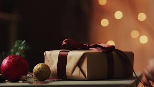 Woman's Hands Unwrapping Christmas Present with Decorations