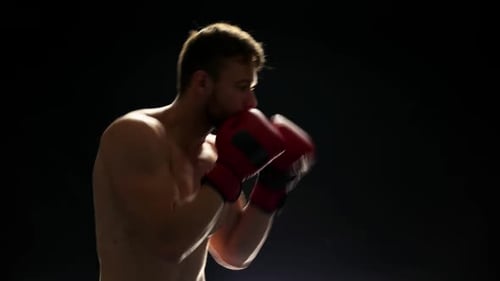Muscular Man Boxing Training in Dark Studio
