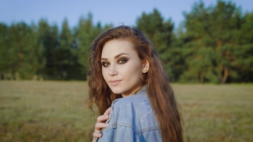 Young Stylish Woman with Long Hair Having Strong Makeup and Posing Along in Summer Field.