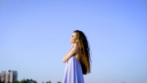 Side View of Sensual Woman with Long Hair Posing on Blue Sky Keeping Eyes Closed.