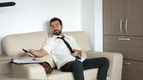 Man Resting on Couch Stretches Back Indoors