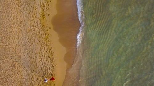 Pareja de enamorados caminando por la playa tomados de la mano