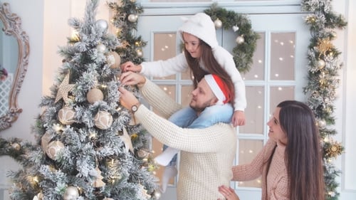 Family Decorates Christmas Tree Together at Home