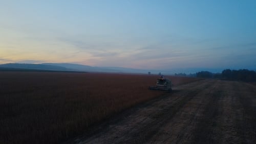 Harvester Working in Field at Dusk from Aerial View