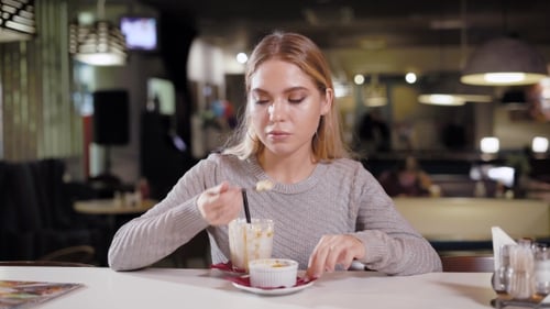 Young Woman Eating Dessert in Restaurant