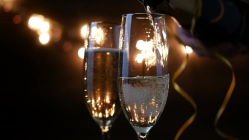 Dos flautas con vino espumoso sobre fondo parpadeante de Bokeh navideño. Ultra metraje.