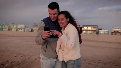 Happy couple walking on the beach at sunset