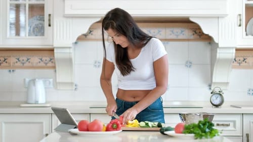 Woman Cuts Vegetables in Bright Kitchen at Home
