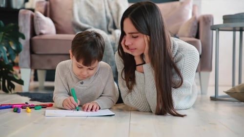Young Woman and Boy Drawing Together on Floor