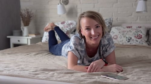 Frau liegt auf dem Bett und lächelt