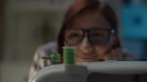 Nahaufnahme einer Frau, die zu Hause eine Fadenspule auf eine Nähmaschine wickelt