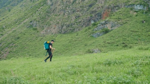The Tourist Makes an Ascent with the Help of Sticks in the Mountains