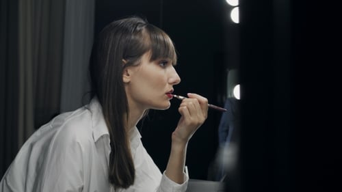 Schöne attraktive Frau schminkt sich vor dem Spiegel Machen Sie sich bereit für Fotoshot und Augenzwinkern
