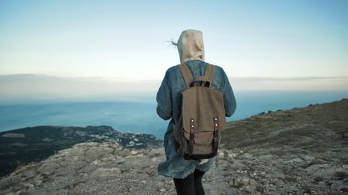 Woman Traveler with Backpack Walking and Enjoying View at Mountains.