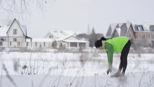 Woman Doing Forward Bend Exercising Outdoors in Winter