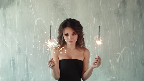 Woman Holding Sparklers Smiling in a Bright Room