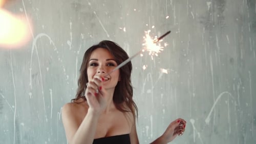 Happy Woman Holding a Sparkler Indoors