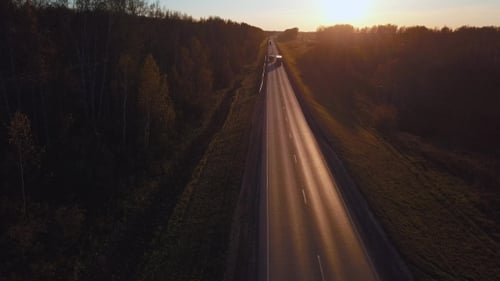 Aerial: the Car with the Container Rides on the Road To the Sunset. Truck Rides the Highway.
