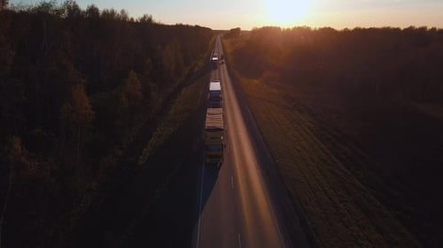 Luftaufnahme: Das Auto mit dem Container fährt auf der Straße zum Sonnenuntergang. Truck fährt auf der Autobahn.