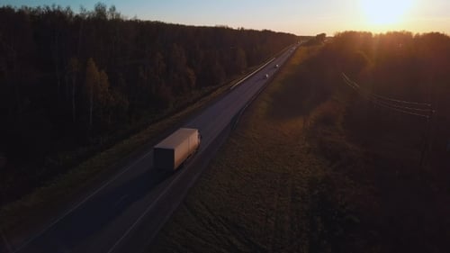 Aerial: the Car with the Container Rides on the Road To the Sunset. Truck Rides the Highway.