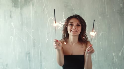 Smiling Woman Waving Sparklers at Birthday Party