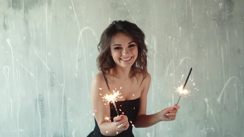 Smiling Woman Holding Sparklers in Bright Room