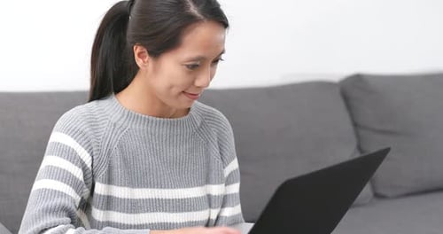 Woman Using Laptop on Sofa at Home