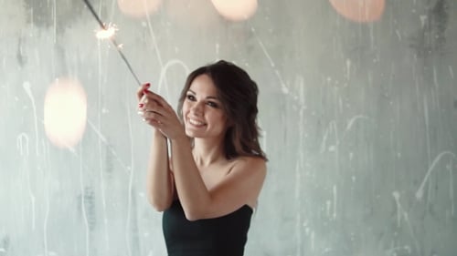 Woman Smiles Holding Sparkler Indoors