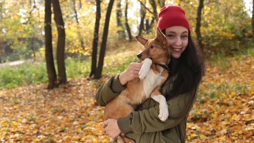 Woman Holds Dog in Colorful Autumn Park