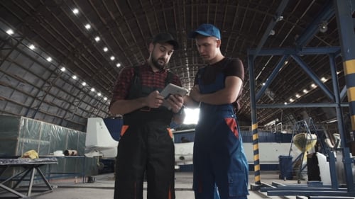 Dos hombres discutiendo en el hangar de aviones