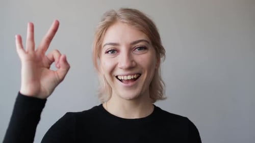 Smiling Blond Woman Makes OK Gesture