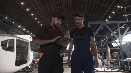 Dos hombres discutiendo en el hangar de aviones