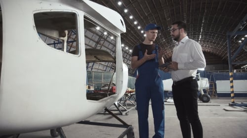 Mechaniker und Zeichner in der Nähe von Flugzeugkarkasse