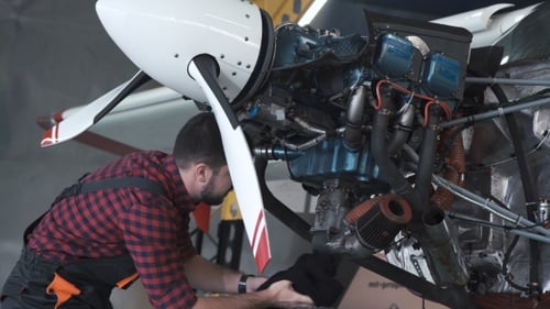 Mann reinigt Flugzeugmotor im Hangar