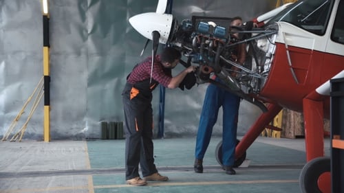 Zwei Mechaniker arbeiten an einem kleinen Flugzeug